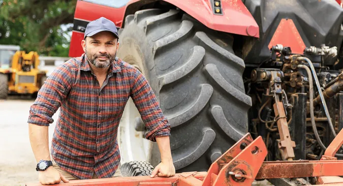 Dieser Landwirt wirkt neben dem riesigen Rad seines Traktors nahezu schmächtig