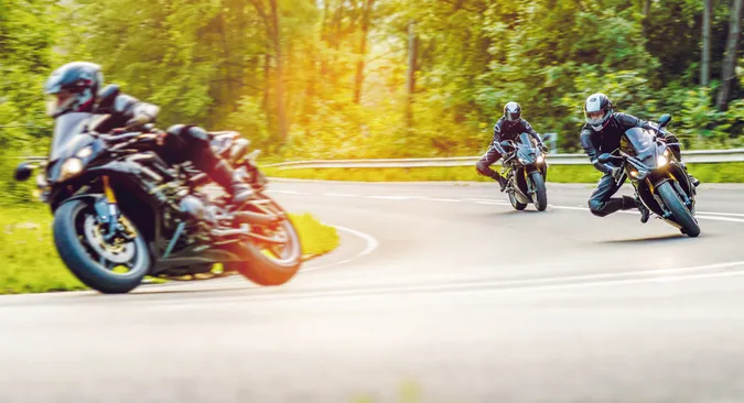 eine Gruppe aus drei Motorradfahrern legt sich an einem sonnigen Spätsommertag ordentlich in die Kurven