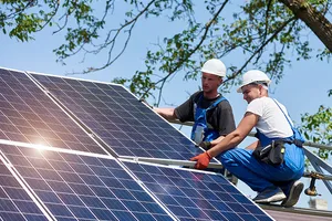 Zwei Solartechniker installieren die letzte Photovotaikplatte auf dem Scheunendach