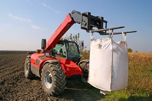Traktor hebt den Big-Bag mit Saatgut aufs Feld