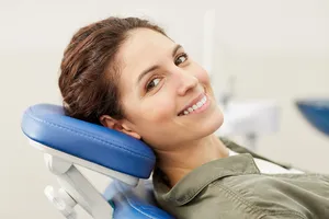 Junge Frau wartet freudig auf die bald beginnende Behandlung zur Zahnreinigung