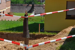 zwei Absperrbänder im Abstand von ca. 50 Zentimetern sichern eine Baustelle an einem Einfamilienhaus