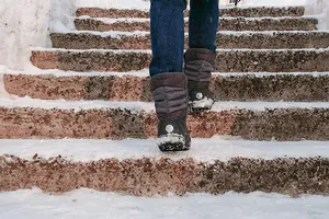Junge Frau geht in warme Stiefel gekleidet eine verschneite Treppe nach oben