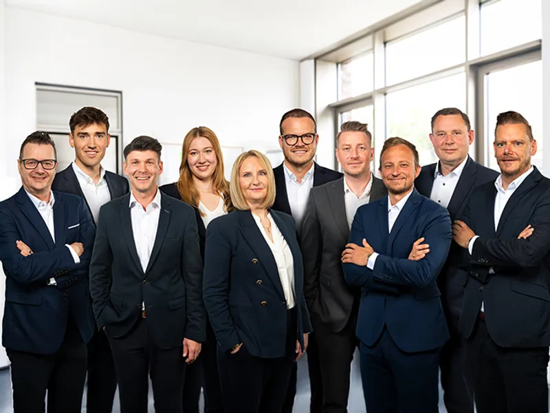 Das Bild zeigt das Team der Bezirksdirektion Hannover vor dem Gebäude mit Mini in der Mitte
