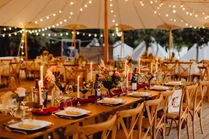 Festlich dekorierte Zelt-Location mit Holztischen und Stühlen 